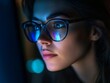 © Littleforest Stocker - Close Up of a Woman’s Face and Eyes Wearing Glasses to Protect Against Harmful Screen Light at Night in a Dimly Lit Room.