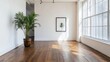 © Elkhan Babayev - A white-walled room with brown wood floors shows a plant in a vase and a framed picture.