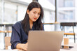 © David - Portrait of Business Asian woman sitting at at laptop and thinking of problem solution, working schedule for employee writing report into notebook while using laptop computer in coworking space