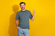 © deagreez - Positive young man in a striped t-shirt pointing with a smile against vibrant yellow background