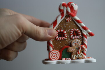 Poster - A person's hand holds a small gingerbread house.