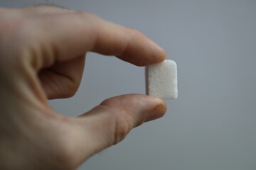 Aufkleber - A person holds a small piece of sugar in their hand, possibly for consumption or use as a sweetener.
