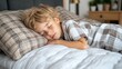 © JO BLA CO - A boy is sleeping on a bed with a pillow. The pillow is white and has a plaid pattern