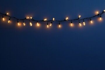 Leinwandbilder - Warm golden Christmas garland lights softly glowing, creating a dreamy bokeh effect over a deep blue background