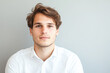 © Kowit - Young man with tousled hair wearing a white shirt against a neutral background.