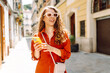 © maxbelchenko - Portrait of a beautiful woman in sunglasses with a phone in her hands walking along sunny streets. Tourist enjoying the weather outdoors. Travel concept.