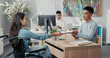 Women is sitting in wheelchair at desk in office across employer they are signing employee contract man extends hand, they shake hands thanking each other for conversation congratulating