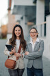 © Zamrznuti tonovi - Two businesswomen smiling and holding digital tablet in urban setting