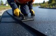 © Анастасия Тимошенко - A man takes measurements after laying asphalt pavement to decide whether to put a new road into operation