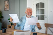 © Migma_Agency - Happy senior man reading good news on documents at home