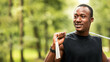 © Prostock-studio - Sport tools and equipment concept. Smiling sporty african guy with jumping rope training at park, looking at free space