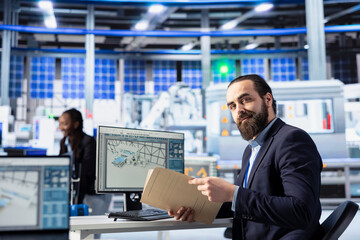 Poster - photovoltaics factory manager reviews paperwork of robot arms performance placing solar panels on co