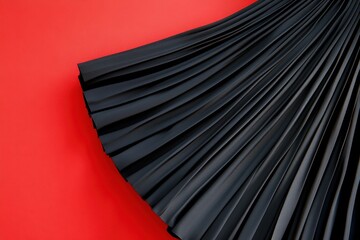Poster - Elegant black pleated fabric draped on vibrant red background showcasing texture and design in a fashion context