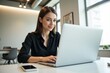 © MT - Young Caucasian Woman Working at a Laptop in a Modern Office Environment with Natural Light and Minimalist Decor