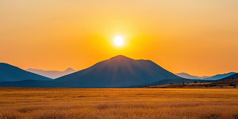 Poster - A stunning sunset over a mountainous landscape, with golden fields stretching beneath a vibrant sky filled with warm hues.