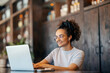 © Dusan Petkovic - Portrait of female freelancer sitting in coffee shop and typing on a laptop.