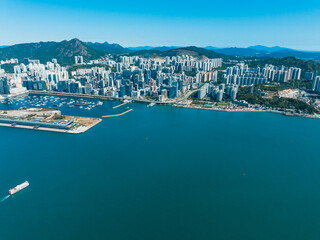 Aufkleber - Aerial panorama of Hong Kong, China, presents a coastal cityscape with a harbor and mountains under a clear blue sky, showcasing urban density.