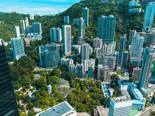 Poster - Aerial panorama of Hong Kong city presents a dense cityscape with towering skyscrapers nestled amidst green hills. A wide view showcases the urban sprawl.