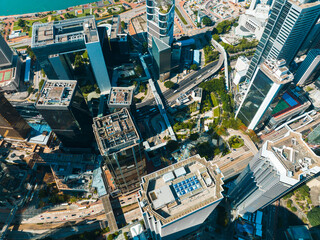 Poster - Aerial panorama of Hong Kong city showcasing dense urban architecture, skyscrapers, roads, and a glimpse of the harbor on a sunny day.