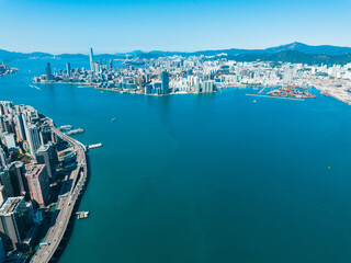 Aufkleber - Aerial panorama of Hong Kong, China, showcasing a sprawling cityscape with tall buildings along the coast and mountains in the distance under a clear sky.