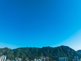 Poster - Aerial panorama of Hong Kong city showcasing mountains and buildings under a bright blue sky.