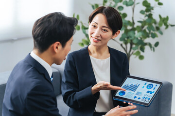 Aufkleber - ロビーでタブレットを見ながら商談する男女ビジネスパーソンのグループ