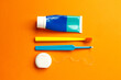 © Krystsina - morning and evening routine dental care from caries tools like toothpaste, toothbrush, tuft toothbrush, floss on orange background
