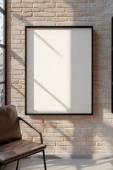 Poster - A large blank frame leans against an exposed brick wall in an industrial loft. A vintage leather chair and black metal shelving complement the soft natural light in the space