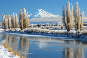 Poster - Snow-covered mountains reflect in a tranquil river lined with tall trees in a winter landscape