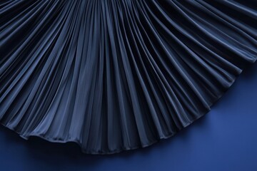 Poster - Elegant black pleated fabric showcasing intricate textures on a blue background in a close-up view perfect for fashion design inspiration
