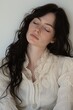 © Ольга Бошарова - A young woman with long dark hair wearing a vintage blouse, resting her eyes in a serene momen