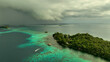 © AmazingAerialAgency - Aerial view of a tropical island with lush greenery and turquoise water under overcast skies, Western Province, Solomon Islands.