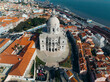 © AmazingAerialAgency - Aerial view of the historic national pantheon and vibrant cityscape with red rooftops at sunset, Sao Vicente de Fora, Lisbon, Portugal.