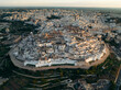 © AmazingAerialAgency - Aerial view of the beautiful medieval town with historic stone structures and fortified walls, Ostuni, Brindisi, Italy.