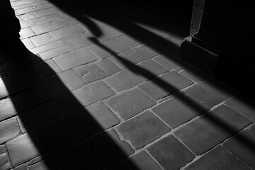 Poster - Shadows stretching across stone tiled floor in black and white