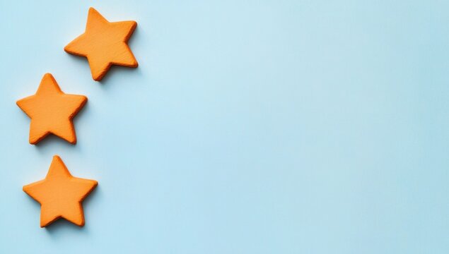 3 orange stars on a light blue background, top view, flat lay. Space for text or logo