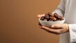 © Yoan Maulana Studio - A Muslim Man is Holding a Bowl of Dates on Brown Background : Suitable for Be Used in Blog Posts, Social Media Posts or Website Content Related to Food, Islamic and Ramadan Theme.