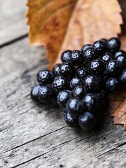 Poster - Close up of fresh black grapes resting on a rustic wooden table with autumn leaves : Generative AI