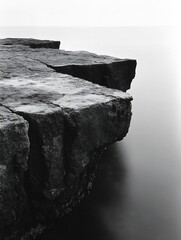Poster - Black and white photograph of rugged cliffs jutting into calm water with soft reflections : Generative AI