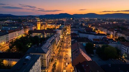 Poster - Aerial view of a vibrant city landscape during sunset with illuminated streets and distant mountain backdrop : Generative AI