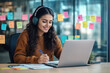 © Imane - Woman watching online video course, training conference inside office at workplace. Office worker in headphones using laptop for remote meeting, writing data in notebook.