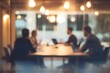 © Johann - blurred photo of an office meeting room with business people sitting around the table with laptops and documents, discussing business plans, talking and working together