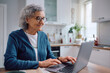 © Drazen - Happy senior woman using laptop at home.