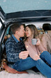 © VolodymyrNadtochii - Young man and woman almost kiss while sitting with sparklers in their hands in the trunk of a car
