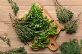 Cutting board with different fresh herbs on wooden background