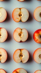 Poster - Overhead shot of apple halves arranged in neat rows on a light gray background. The apples are red and have a creamy white interior. 