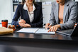 © Phushutter - Two female lawyers in business suits meet at wooden desk, shaking hands over contract paper. wooden gavel and scales justice as discuss legal compliance, corporate law, dispute resolution.