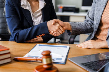 two female lawyers in business suits shake hands at wooden desk, finalizing legal agreement. wooden 