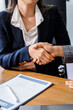 © Phushutter - Two female lawyers in business suits shake hands at wooden desk, finalizing legal agreement. wooden gavel and scales represent justice as they discuss corporate law, compliance, dispute resolution.