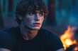 © ALL YOU NEED studio - Close-up portrait of a young man with striking blue eyes, tousled brown hair, and a strong jawline, illuminated by the warm glow of a fire, set against a twilight forest background with soft bokeh